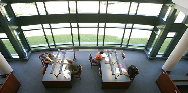 Students study near large windows in the law library